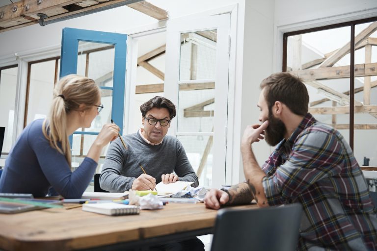 Female and male designers brainstorming at design studio desk meeting