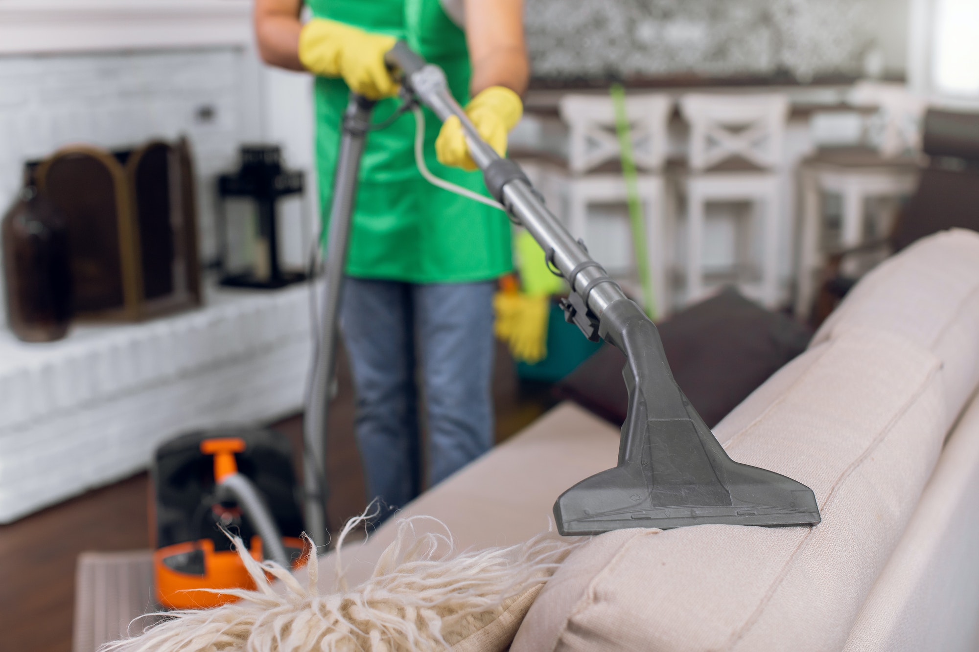 Close up of male cleaner vacuuming cozy sofa