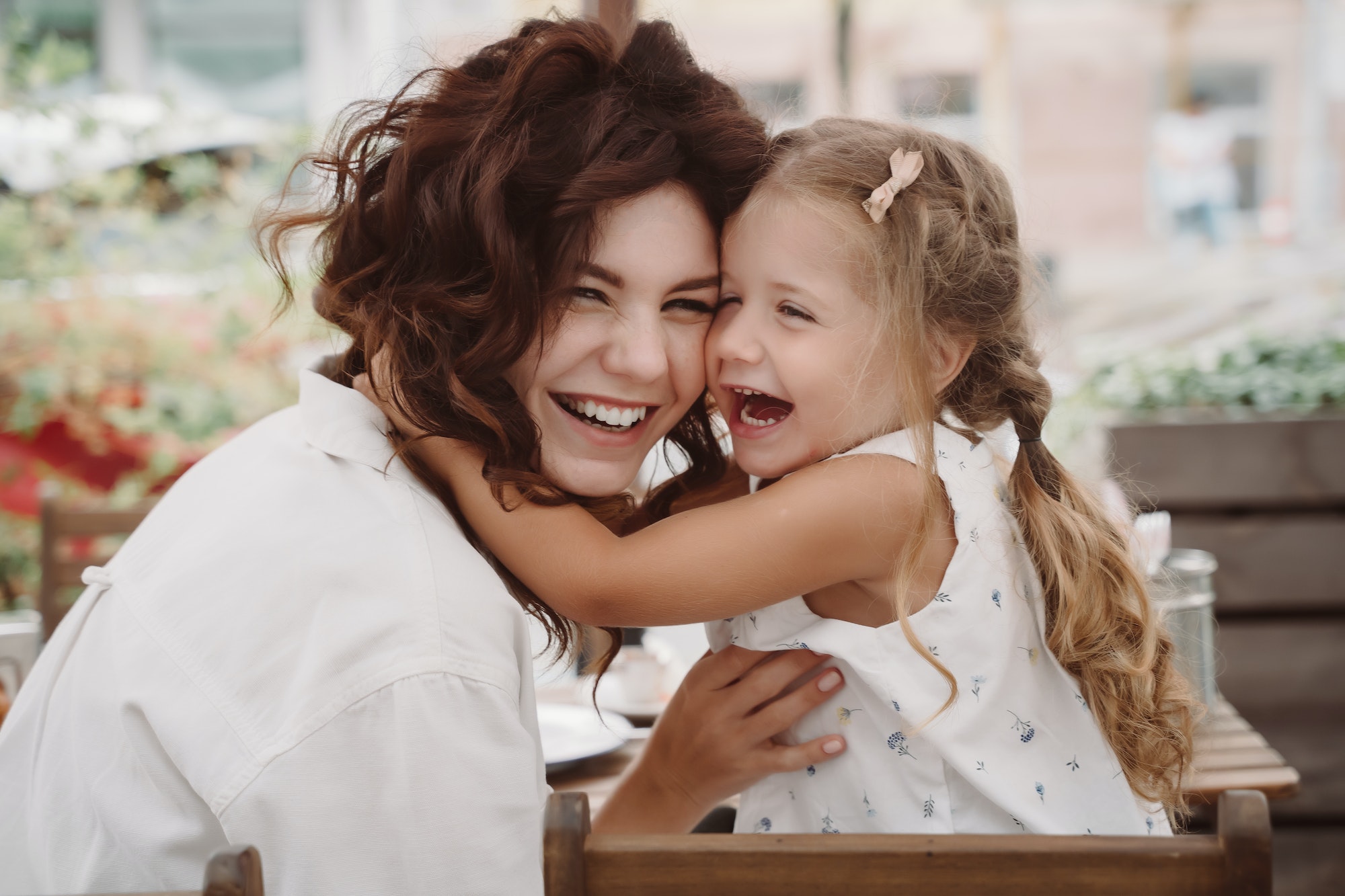 Cute little girl and her beautiful young mom hug each other